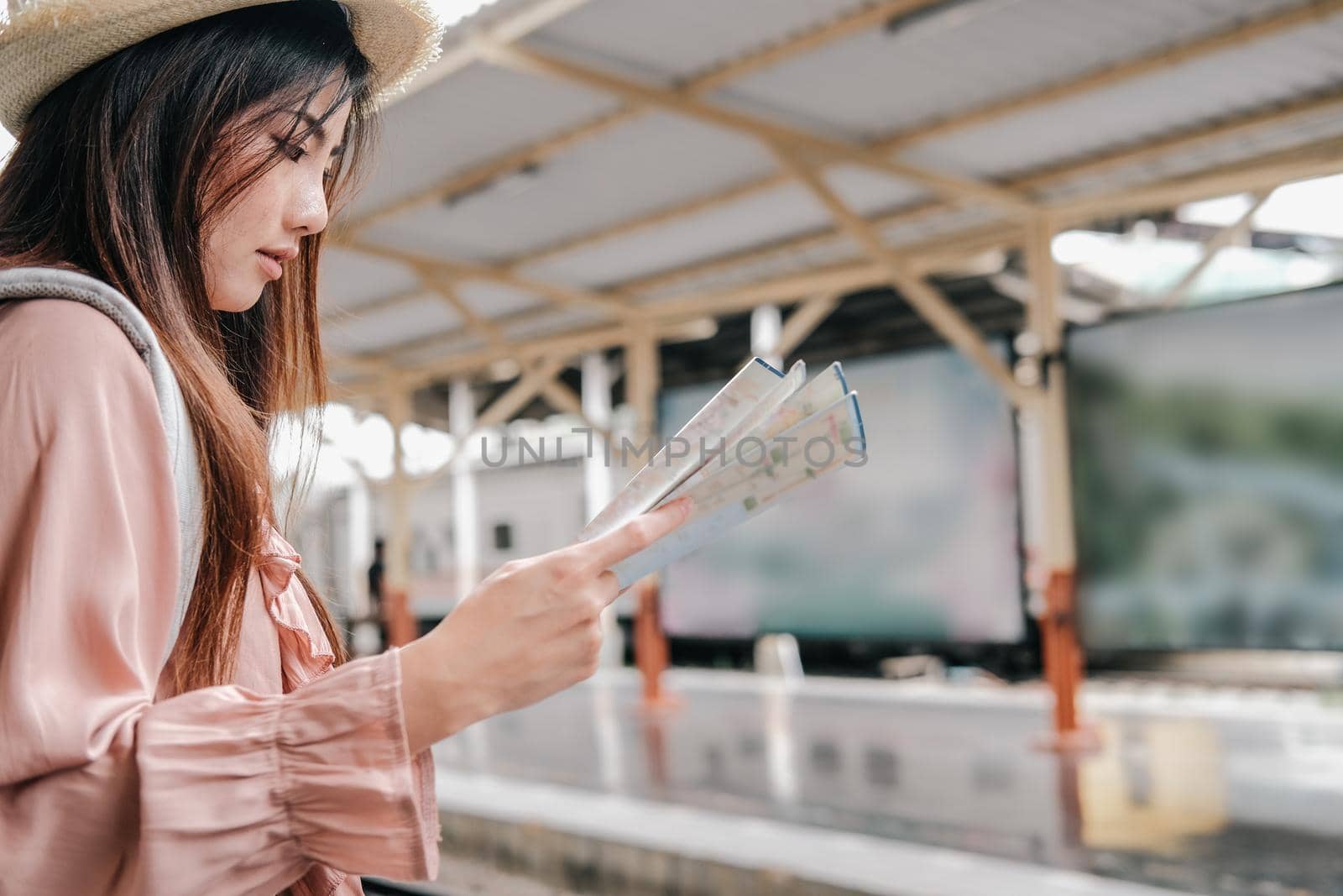 woman backpacker traveler looking at map with backpack at train station while waiting for train. journey trip travel concept by pp99