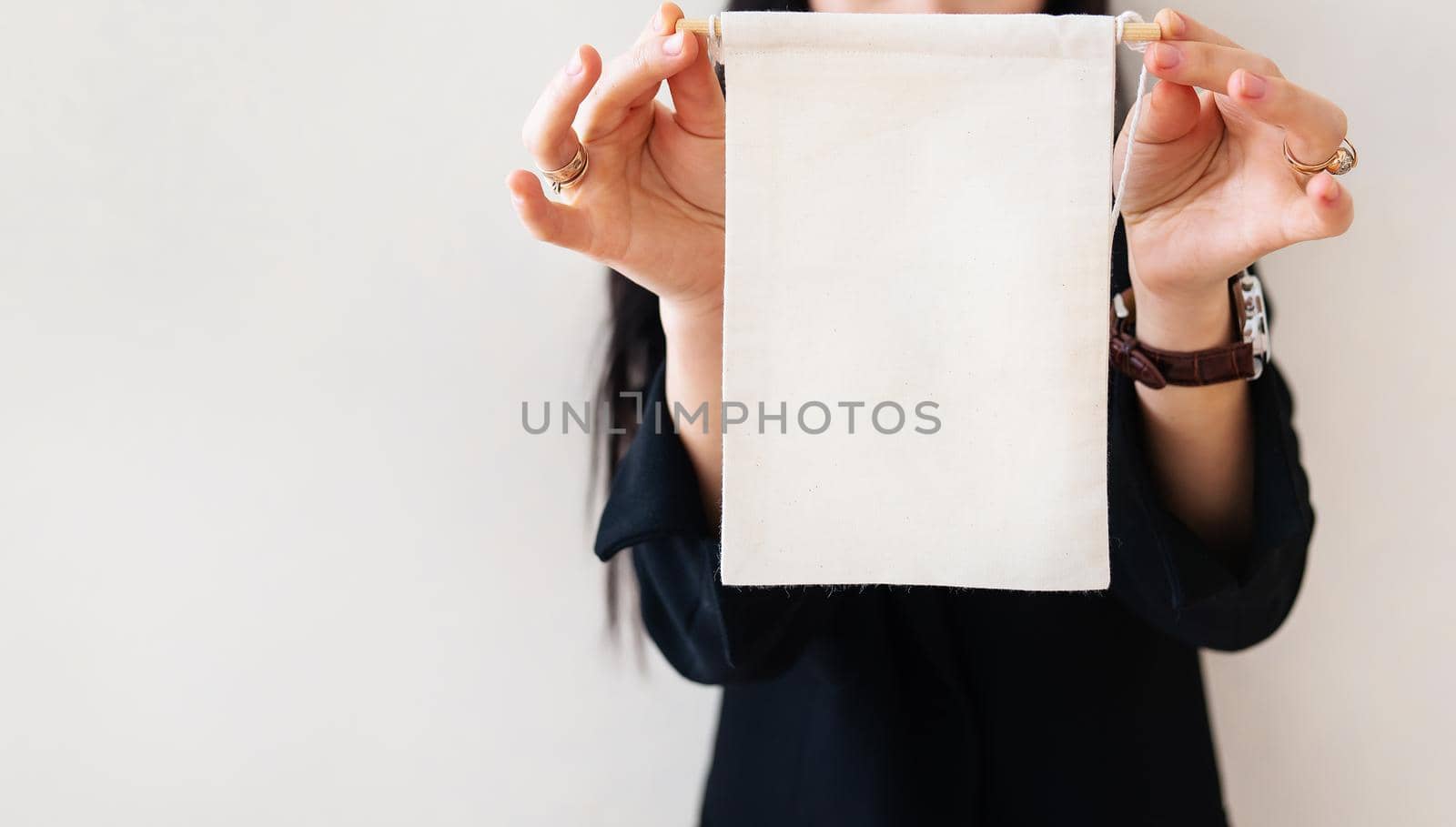 Young business woman in a black suit shows a blank white billboard on a white isolated background. Place for the inscription on the poster. by sfinks