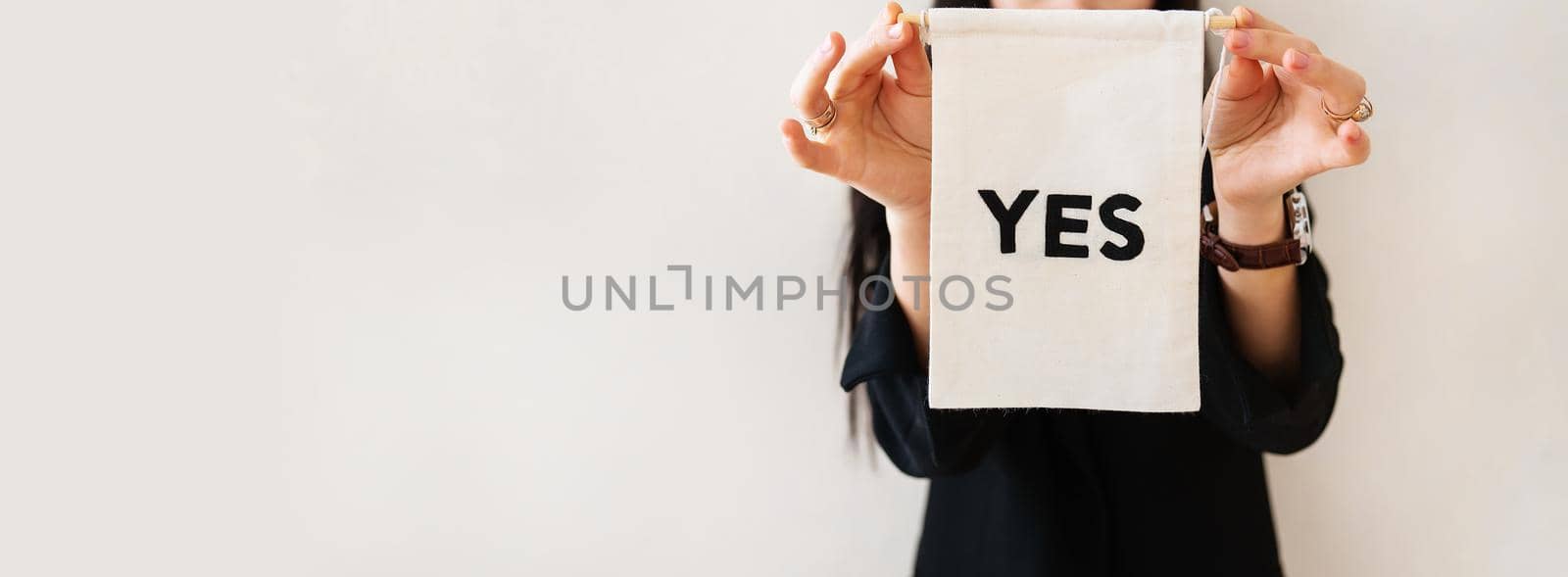 Young business woman in a black suit shows a blank white billboard on a white isolated background. The poster says yes. Concept for business and advertising. Banner. by sfinks