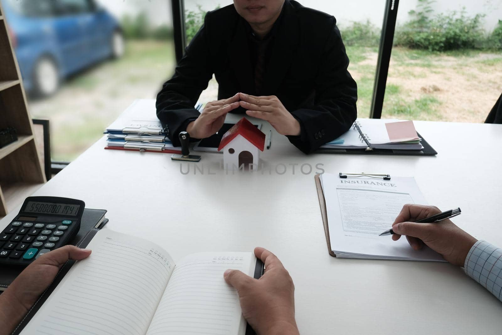 hand protecting house model. client signing home insurance contract. property safety and security concept