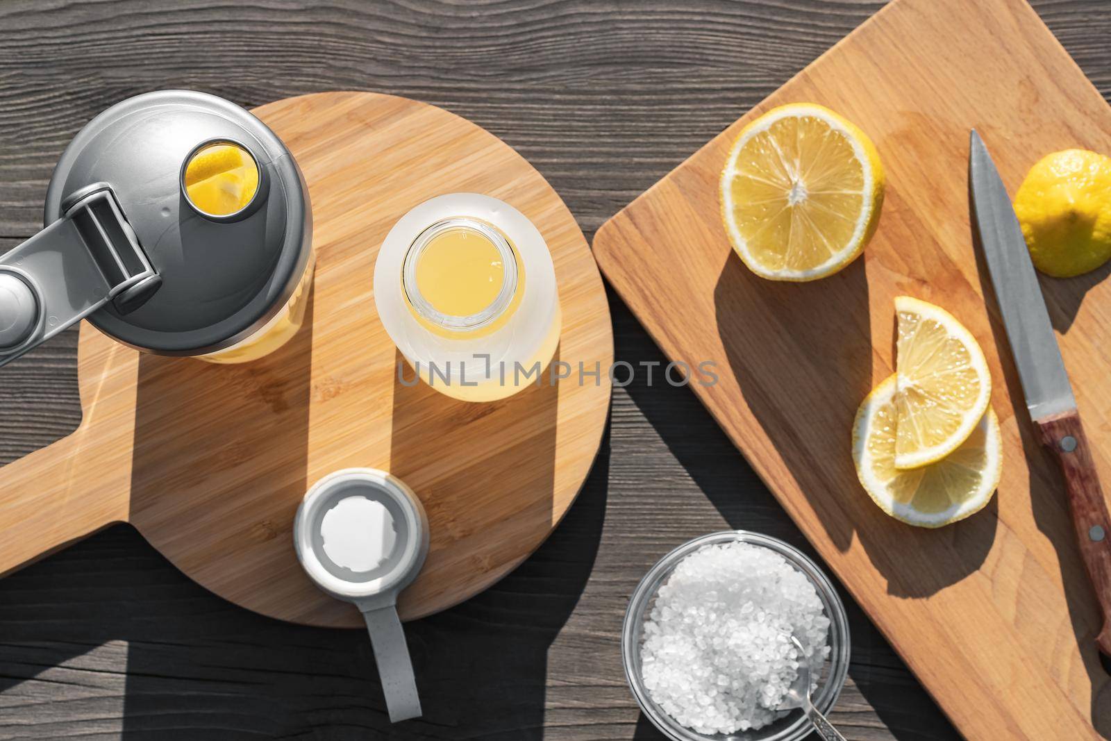 Cooking fresh homemade isotonic from natural ingredients - salt, lemon and mineral water. Top view, flat lay, selective focus by galsand