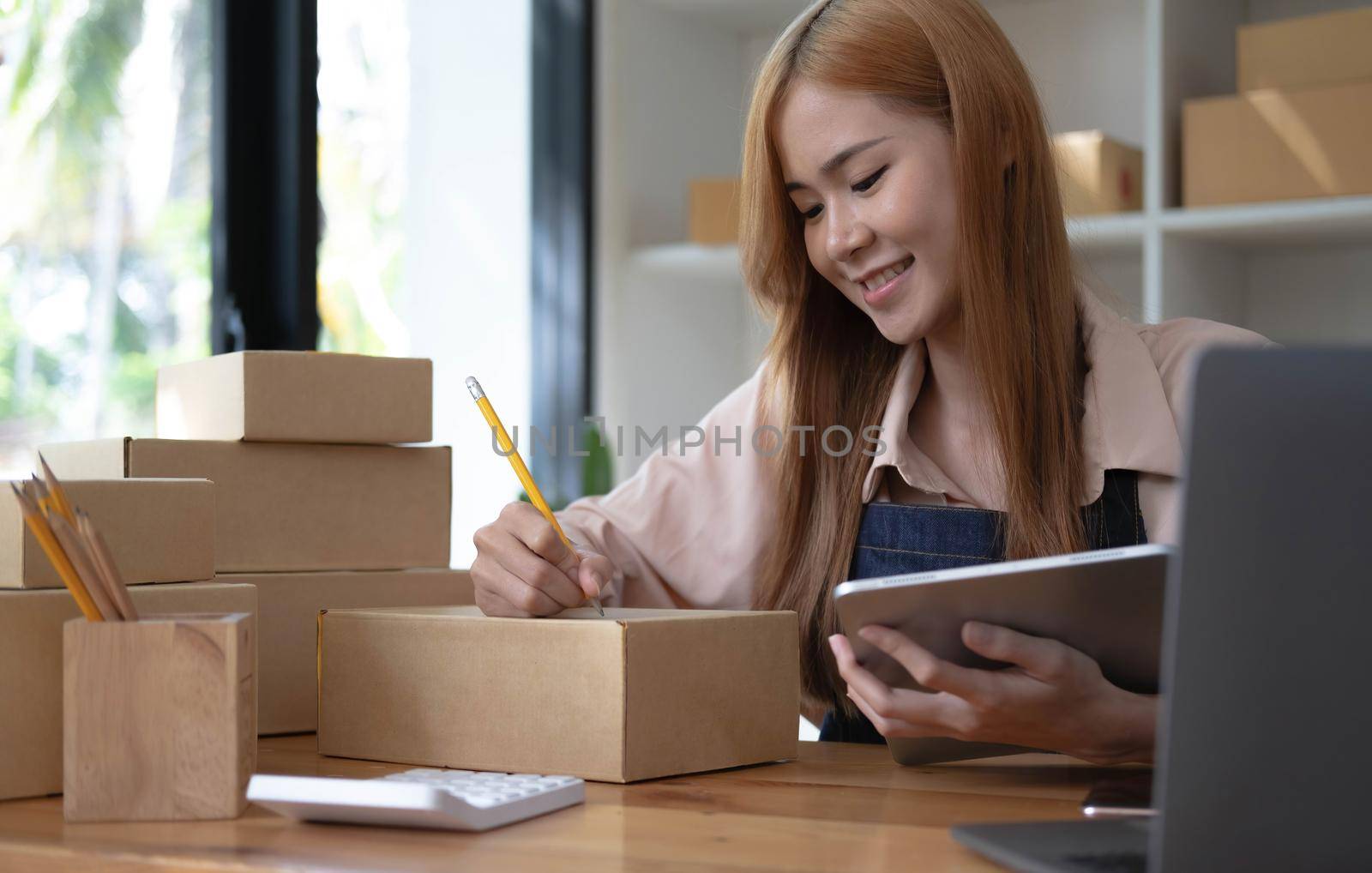 Startup successful small business owner sme beauty girl stand with tablet smartphone in coffee shop restaurant. Portrait of asian tan woman barista cafe owner. SME entrepreneur seller business concept by wichayada