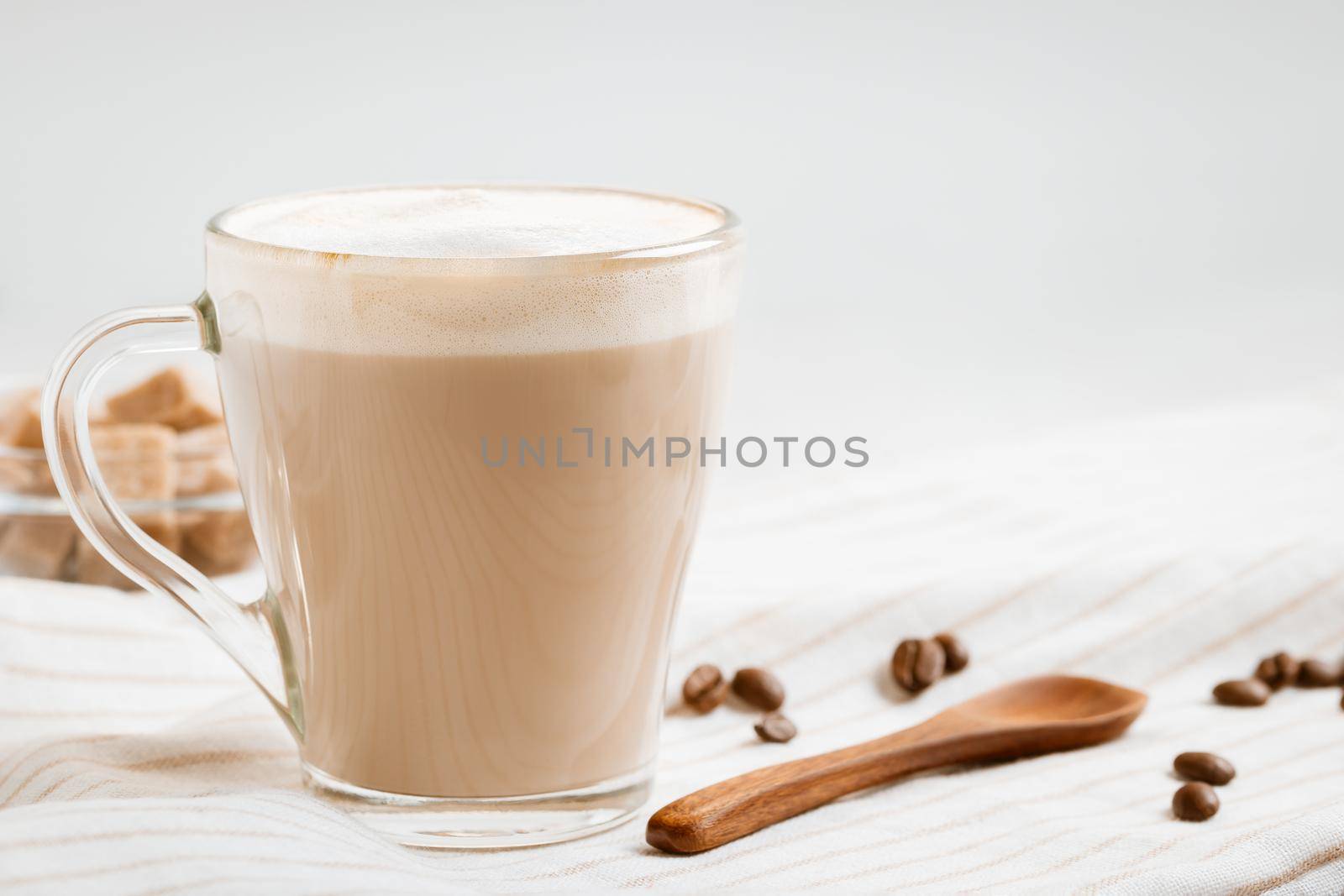 Latte coffee with foam on a light kitchen table, copy space.