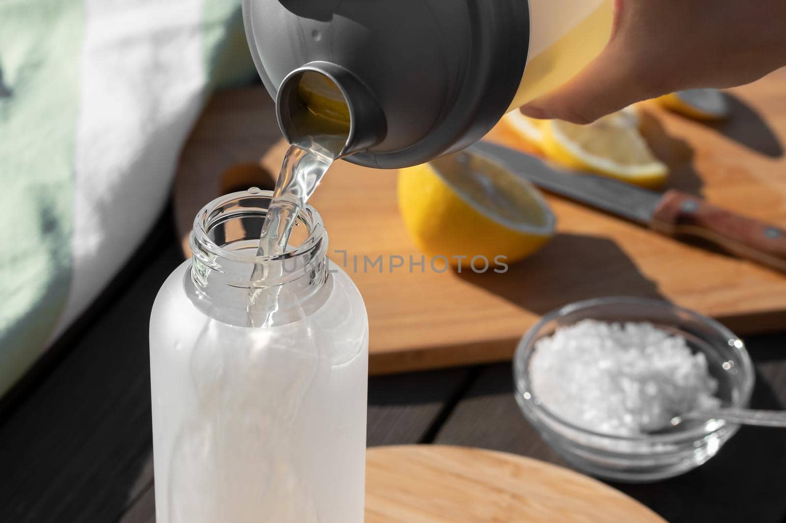 Cooking fresh homemade isotonic from natural ingredients - salt, lemon and mineral water. Pouring into a bottle.