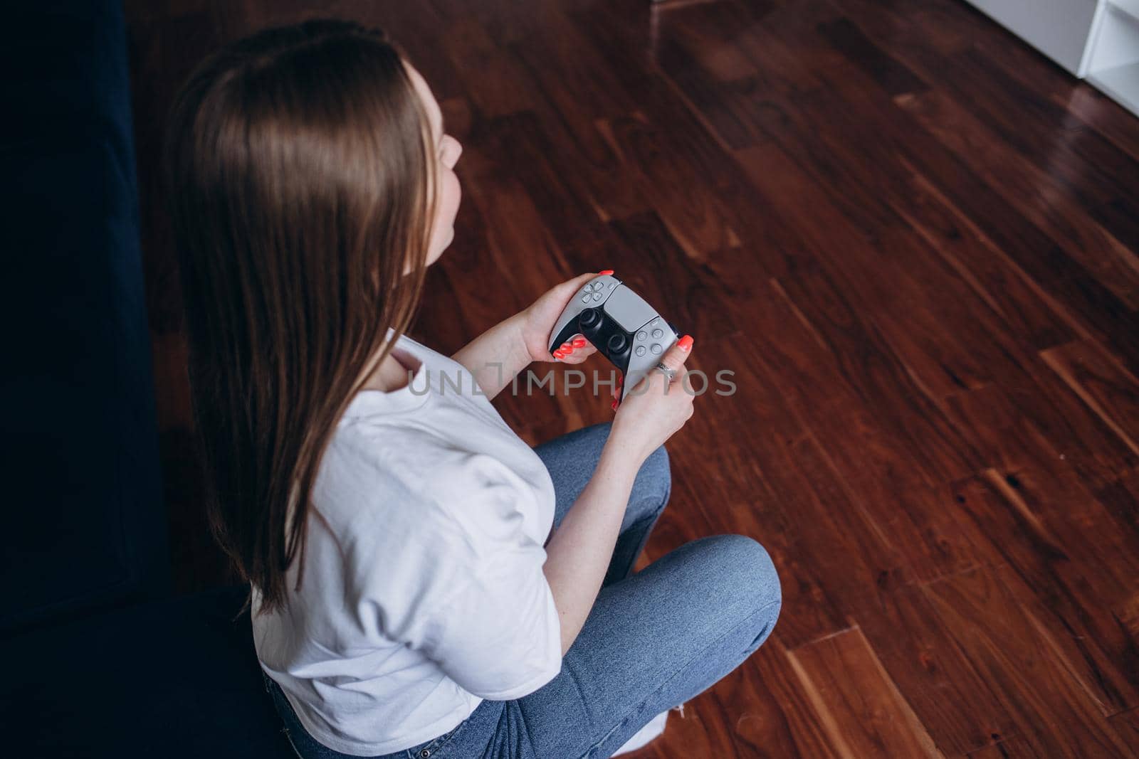 A young woman is playing a game console. Girl gamer and computer video games. The streamer holds a joystick in her hands. Person at home at night. by fentonroma