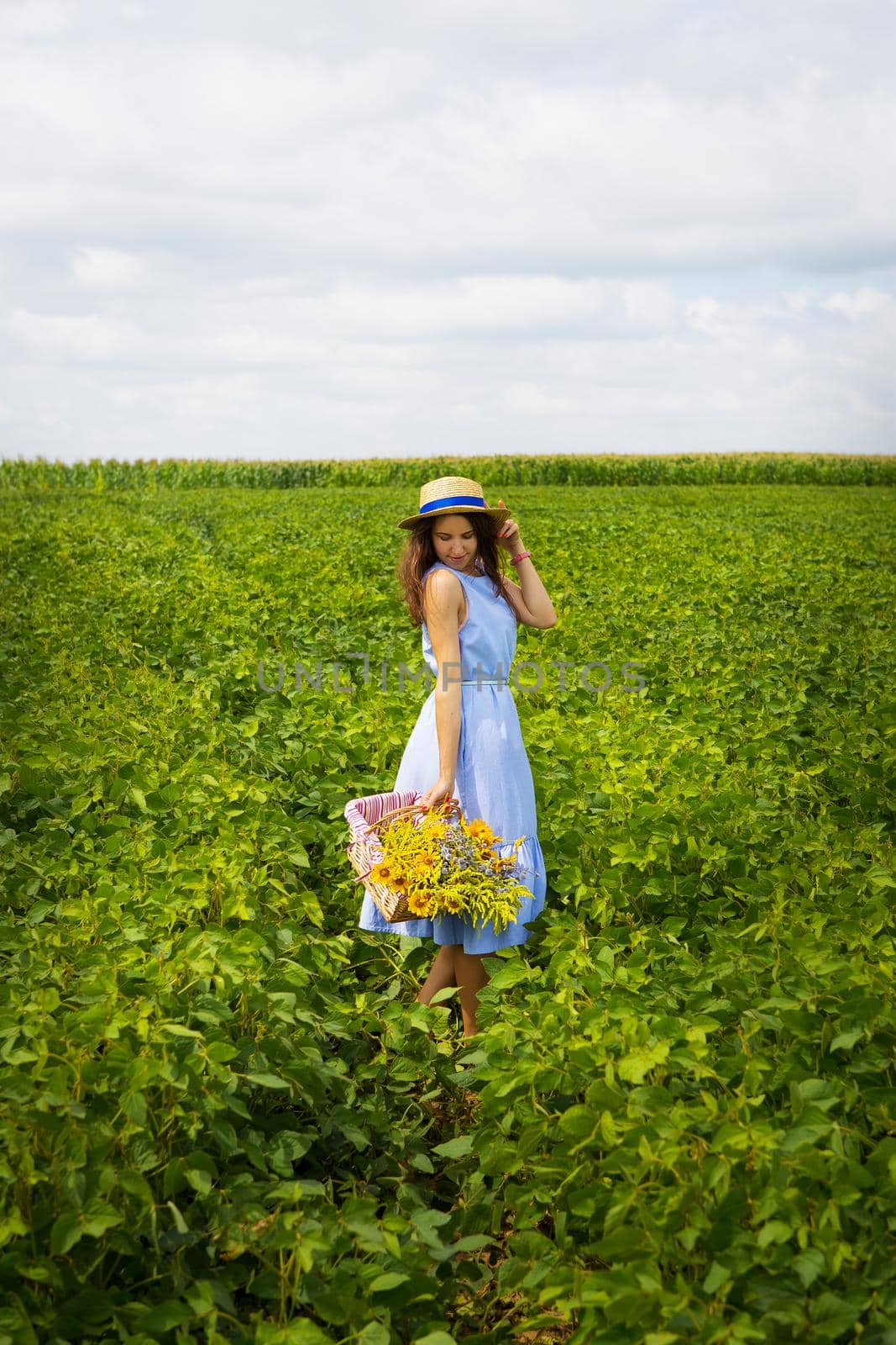 beautiful girl in a hat and blue board is standing on a green field.