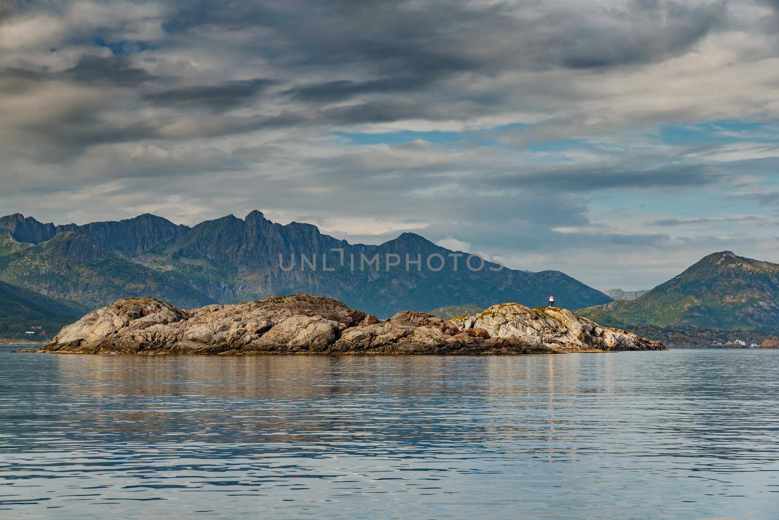 Norwegian seascape, rocky coast with dramatic skies, the sun breaks through the clouds, sheer cliffs, small islands illuminated by the sun. High quality photo