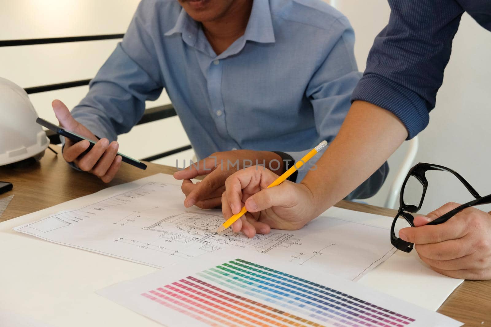 architect interior designer working with architectural drawing of house & color swatch catalog