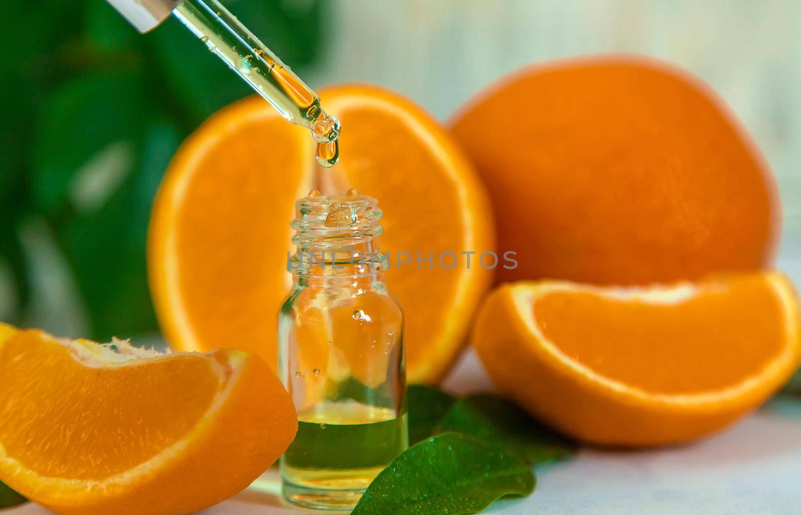 Orange essential oil in a small bottle. Selective focus. by yanadjana