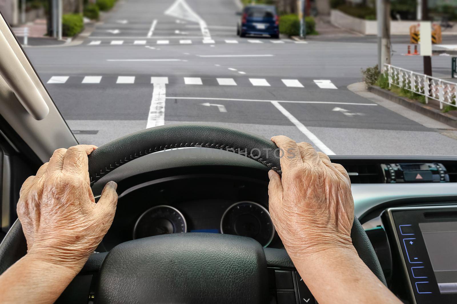 Senior woman driving a car on street in city.