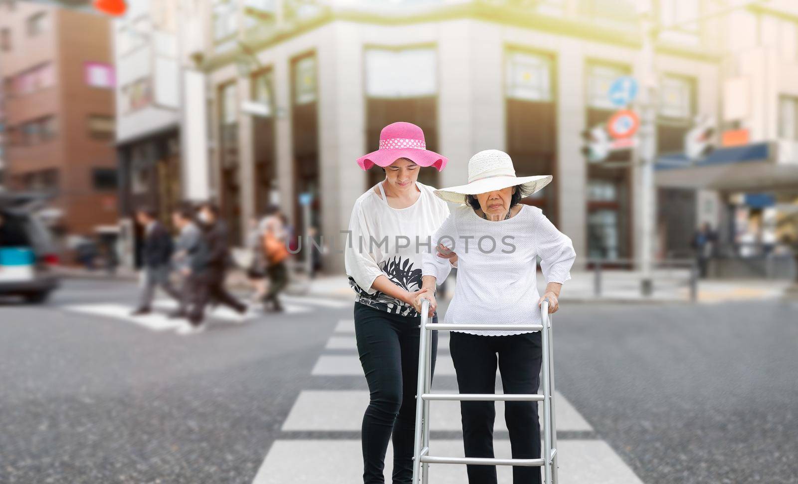 Daughter take care elderly woman walking across the street in downtown
