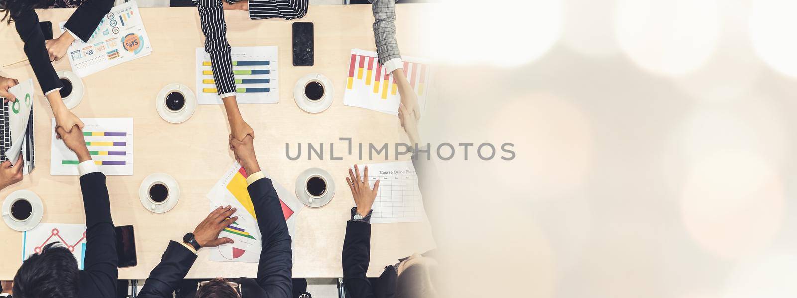 Group business people handshake at meeting table in office together with confident shot from top view . Young businessman and businesswoman workers express agreement of investment deal. broaden view