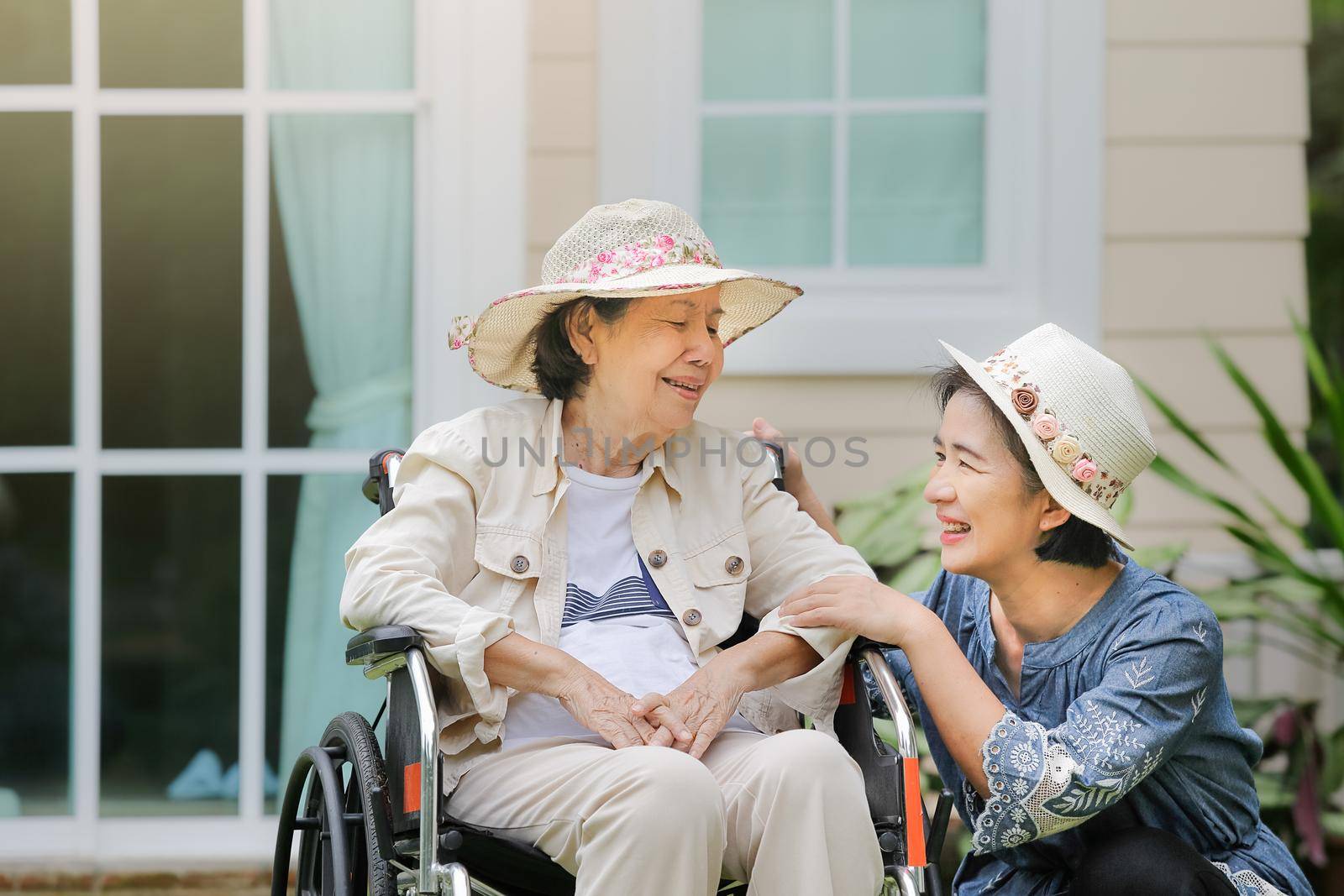 Elderly woman relax on wheelchair in backyard with daughter