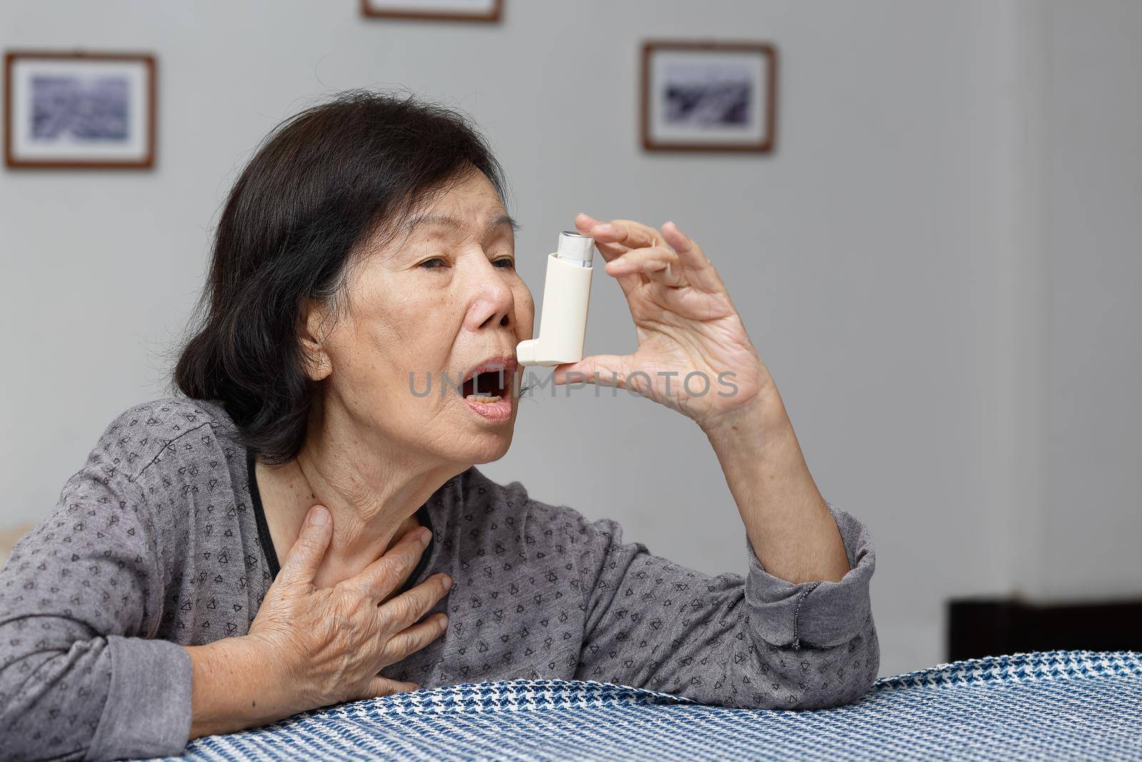 Elderly woman choking and holding an asthma spray