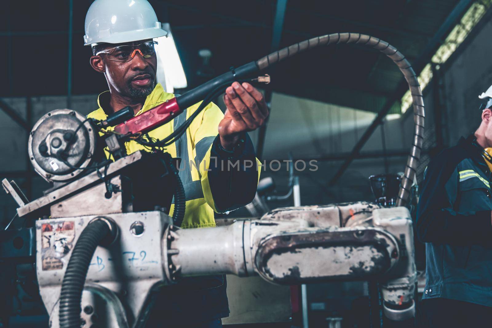African American factory worker working with adept robotic arm in a workshop . Industry robot programming software for automated manufacturing technology .