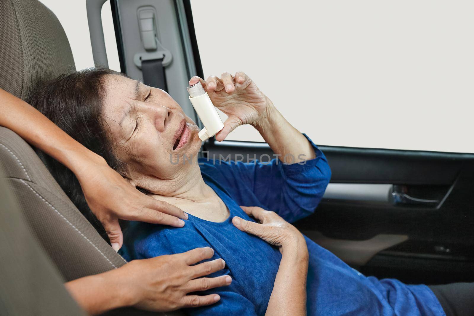 Elderly woman choking and holding an asthma spray inside car on the way