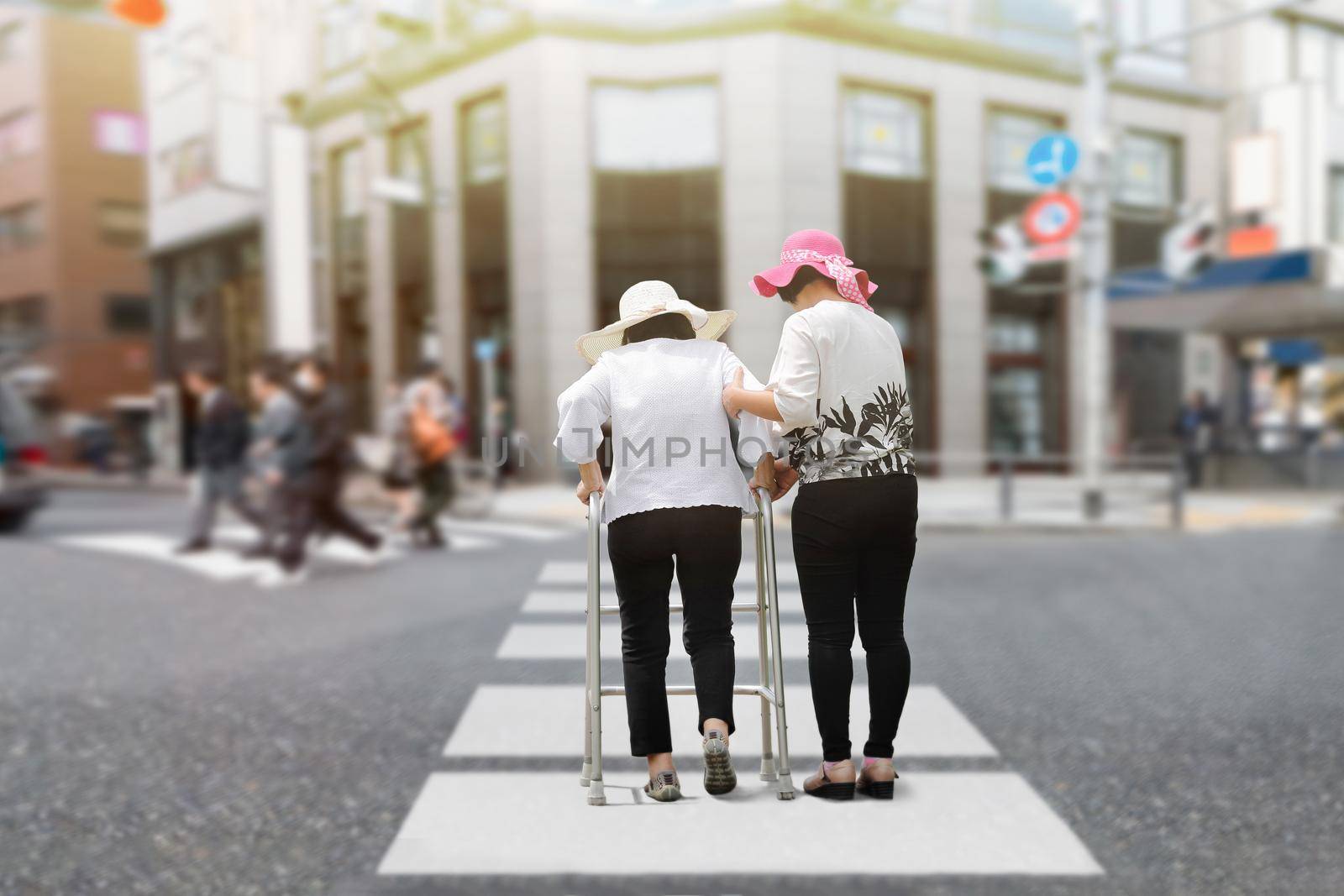 Daughter take care elderly woman walking on street in strong sunlight. by toa55