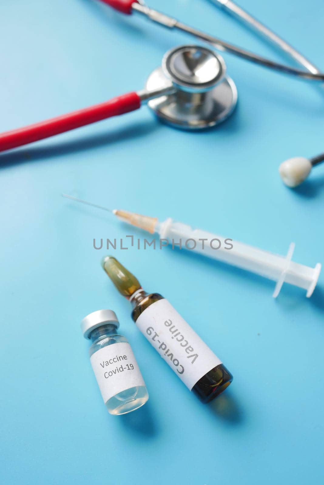 Close up of coronavirus vaccine , stethoscope and syringe on blue ,