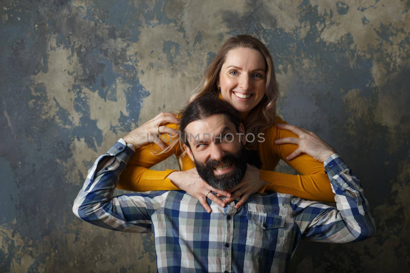 Happy adult couple hugging, smiling wide and looking at camera by BY-_-BY