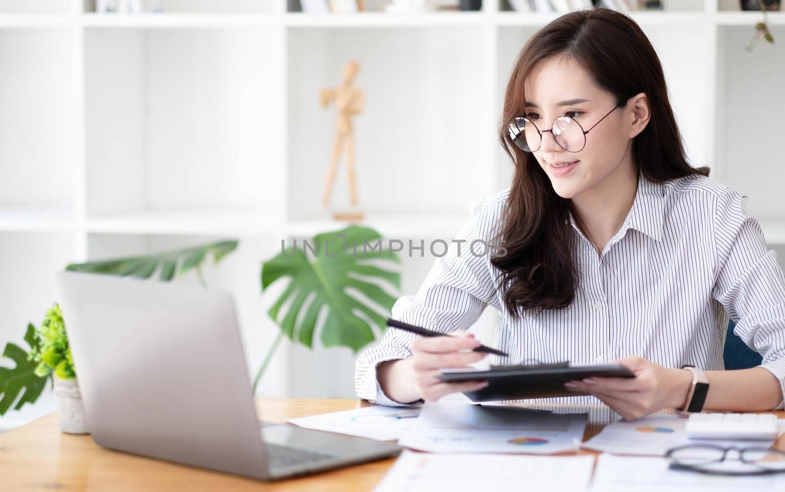 Smiling asian business woman sitting in a modern office. by wichayada