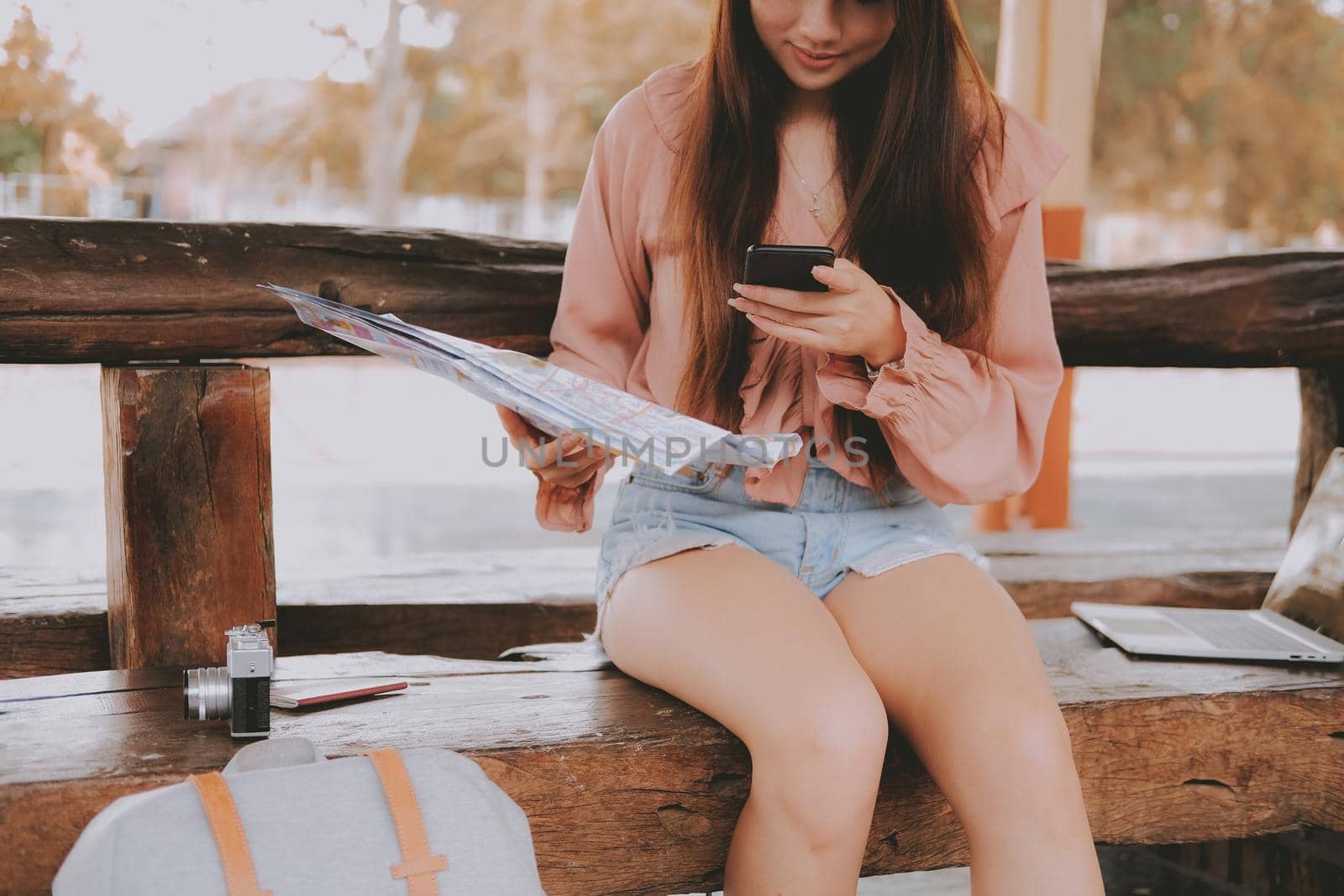 young woman traveler with mobile smart phone & map at train station. Travel journey trip concept