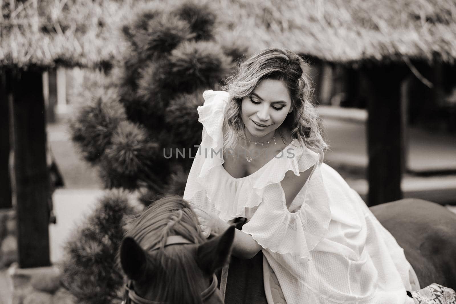 A woman in a white sundress riding a horse near a farm. black and white photo by Lobachad