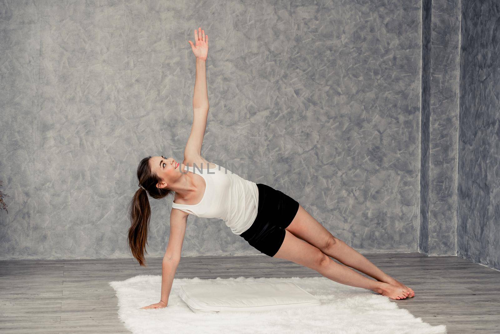 Young beautiful woman do yoga exercise on carpet at home living room. Healthy lifestyle and relaxation.