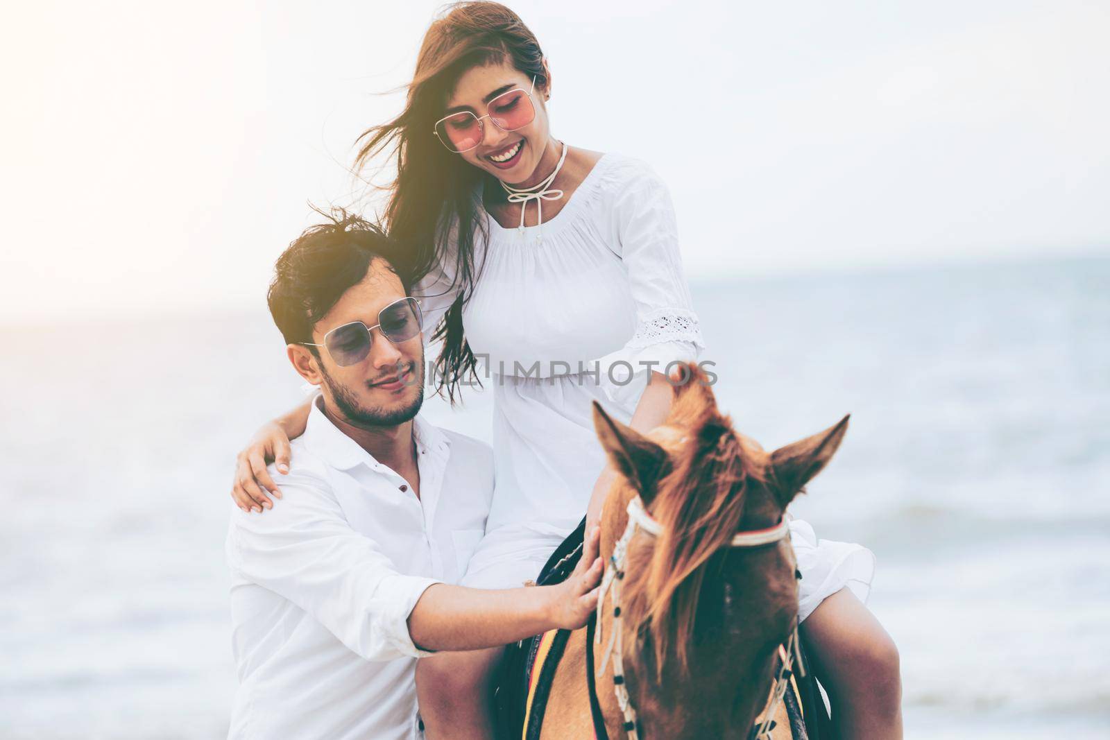 Young couple goes honeymoon horse riding on the beach in summer vacation.