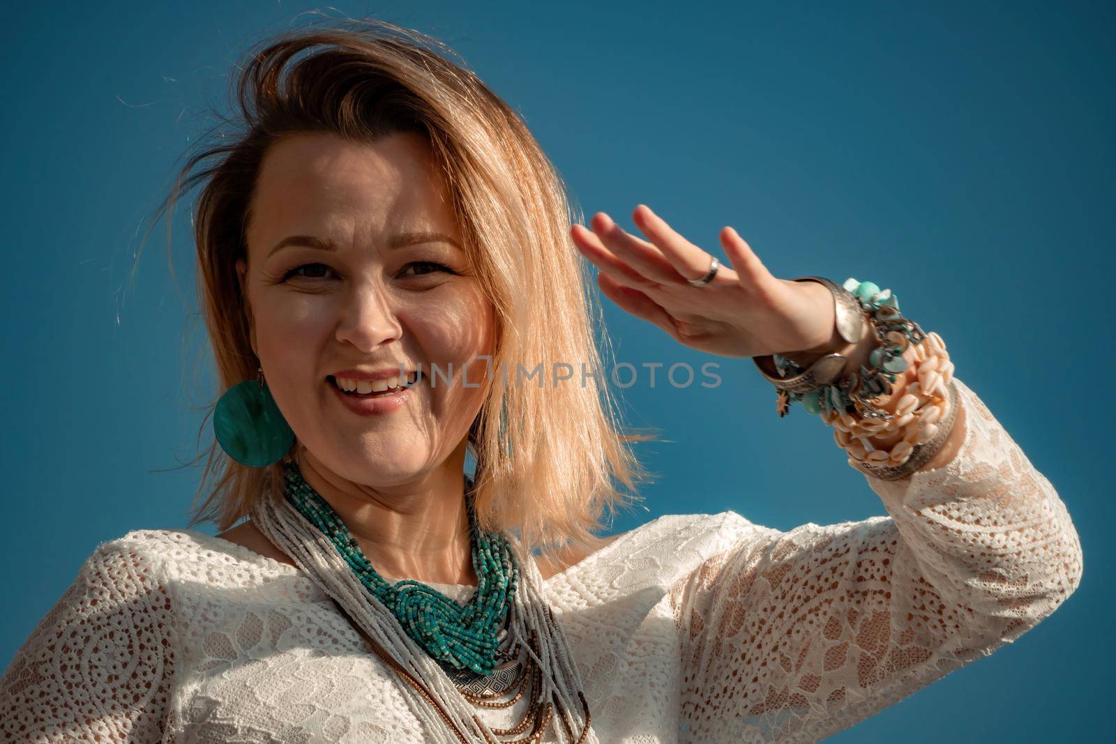 Woman in bohemian clothing on beach at sunset. Boho style for fashionable look on resort. Middle aged well looking woman in white dress and boho style braclets. Summer fashion by panophotograph