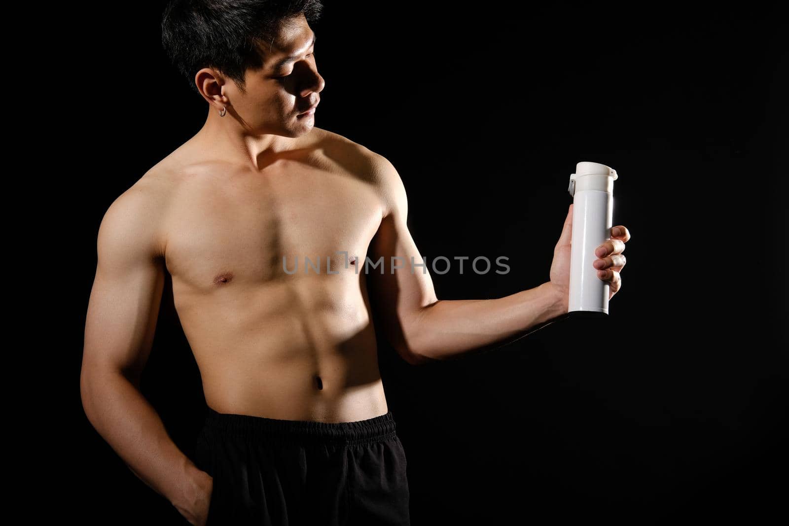 portrait of athletic muscular bodybuilder man with naked torso six pack abs holding protein drink. fitness workout concept