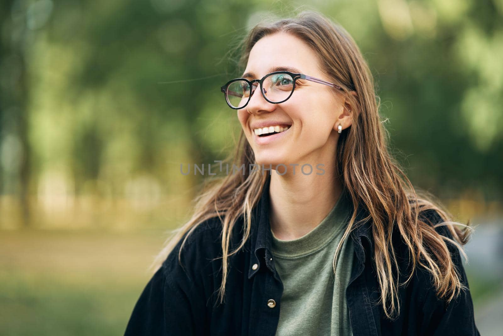 Portrait of a smiling young girl with glasses in the park. High-quality photo