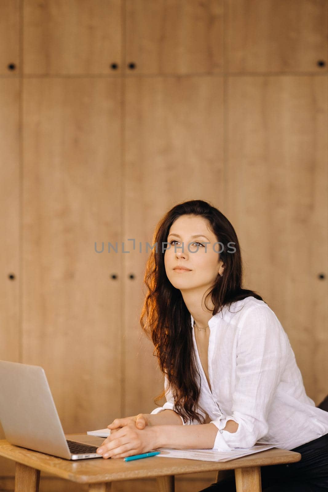 Beautiful woman sitting in the office working on a laptop by Lobachad