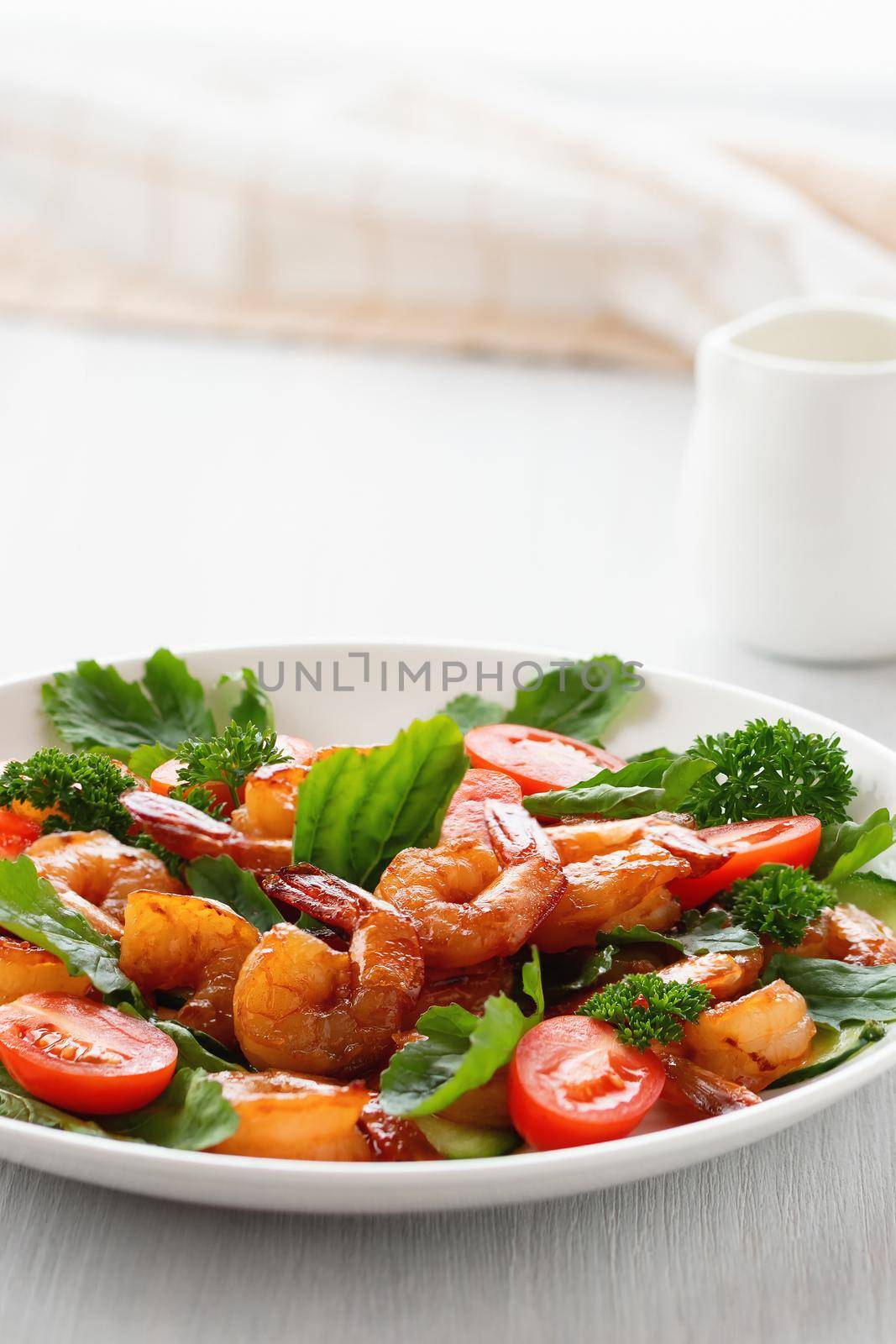 Fresh salad of shrimps, tomatoes, arugula and herbs on a white plate. vertical image by galsand