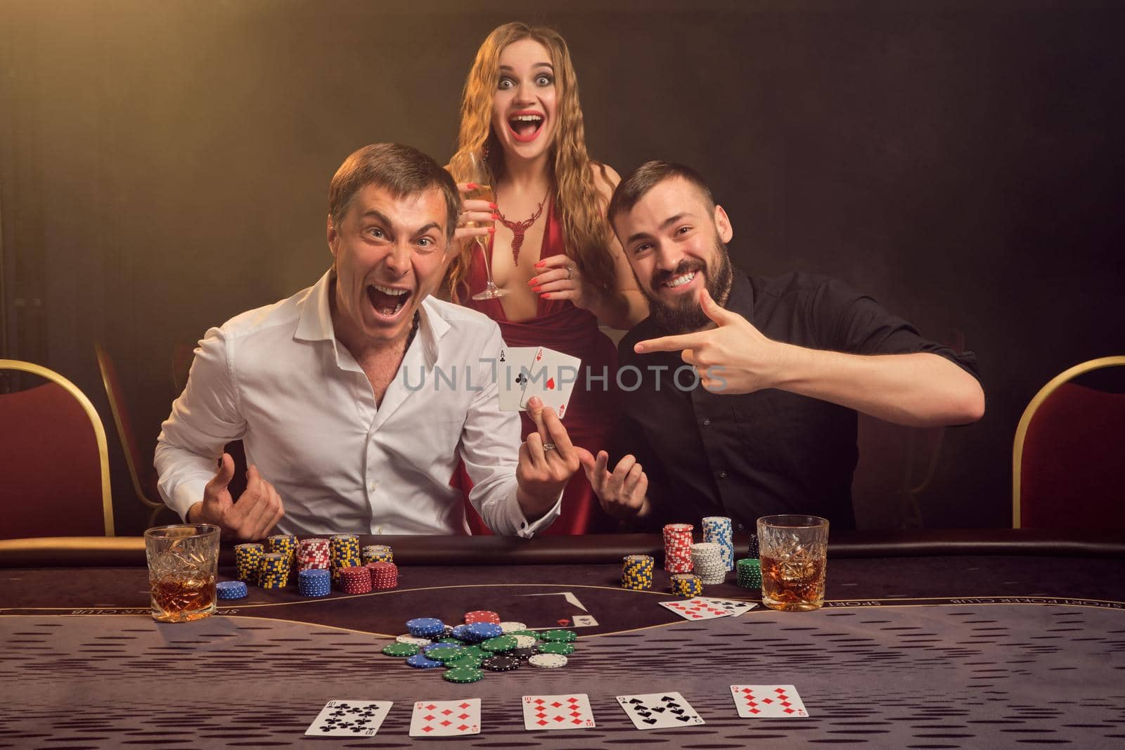 Group of a young wealthy friends are playing poker at a casino. by nazarovsergey