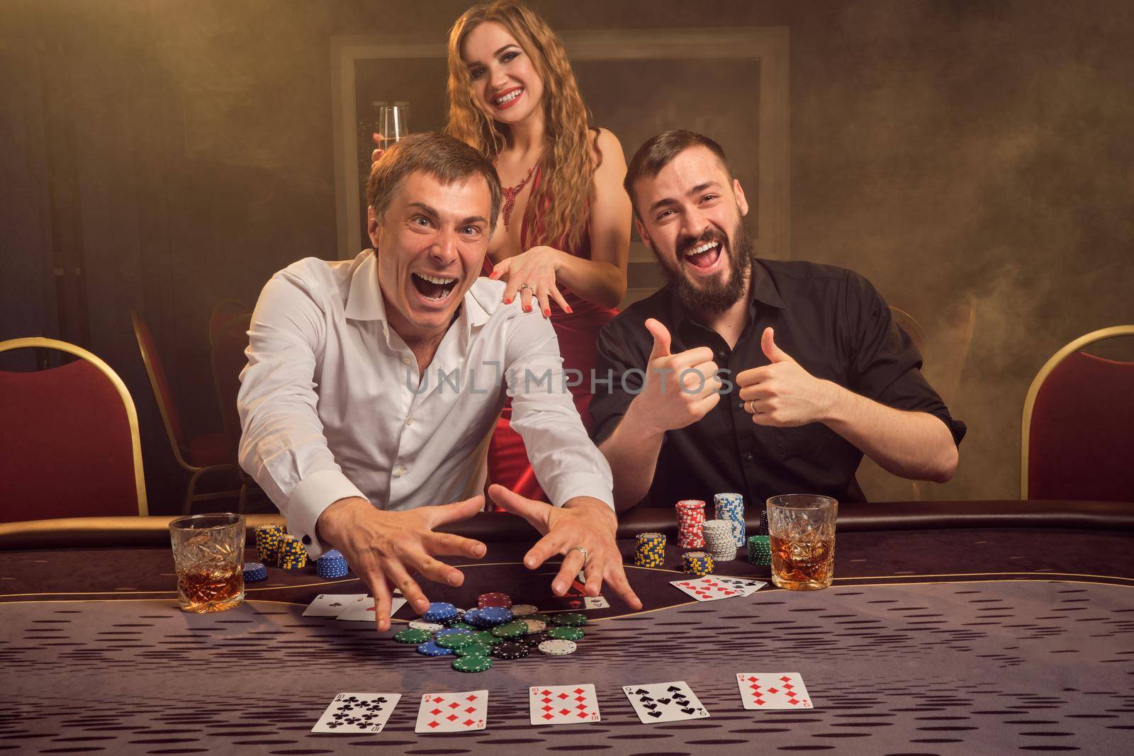 Group of a young wealthy friends are playing poker at a casino. by nazarovsergey