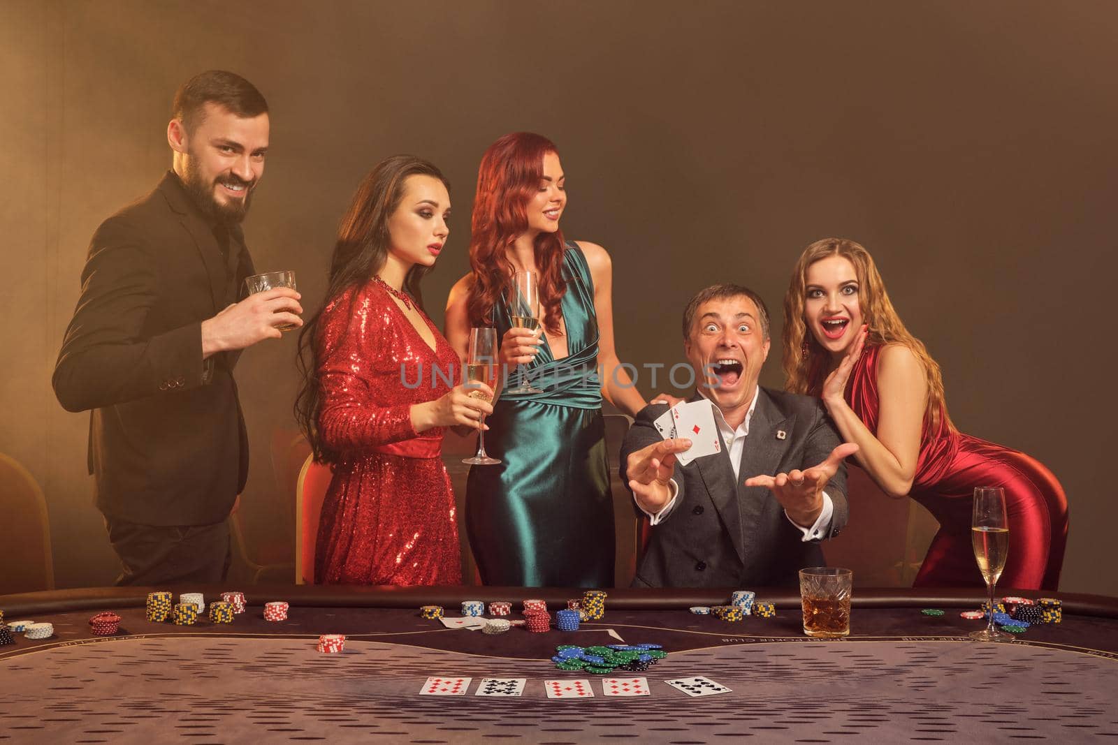 Group of a young wealthy friends are playing poker at a casino. by nazarovsergey