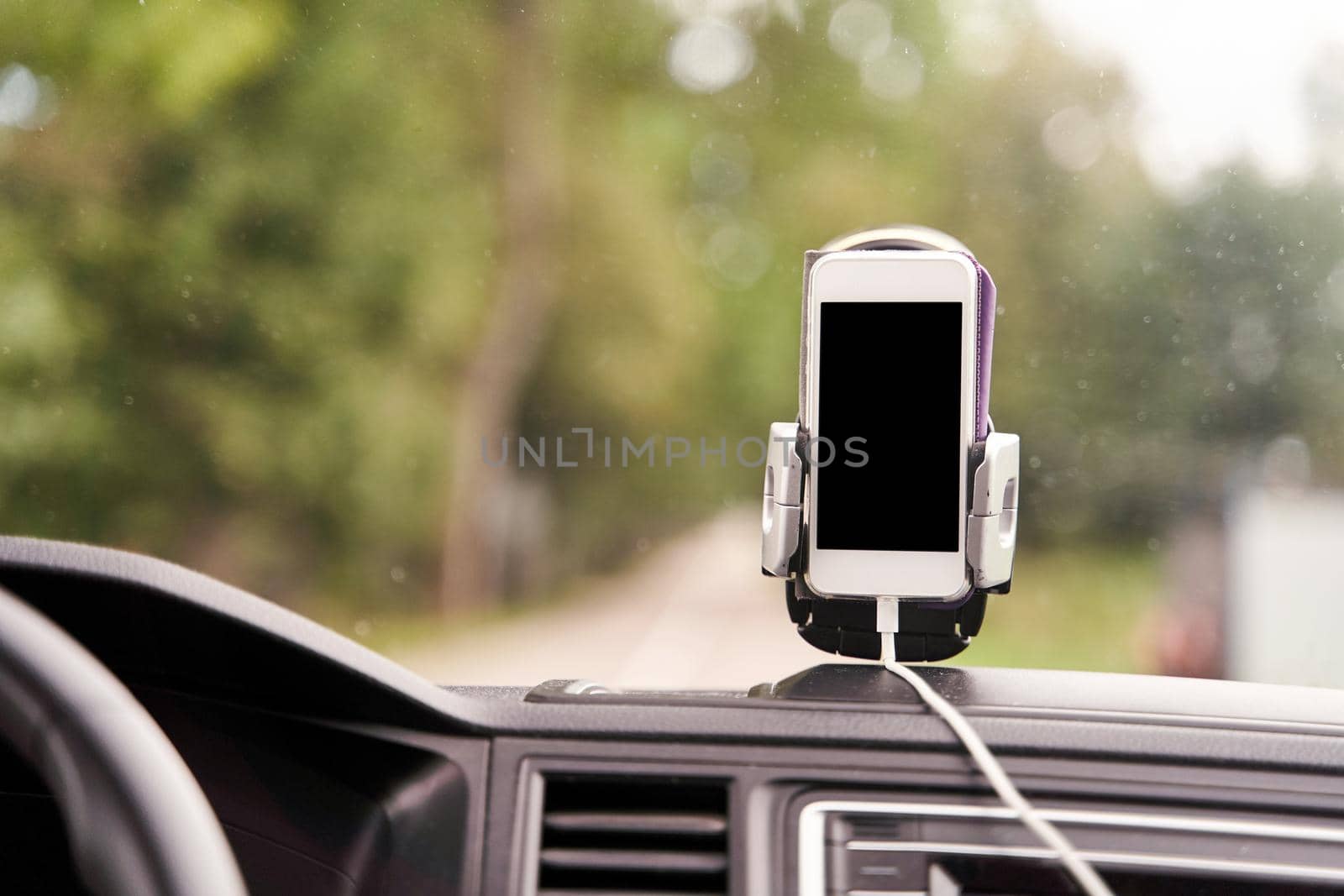 A white smartphone on a stand in the car is used for navigation. by driver-s