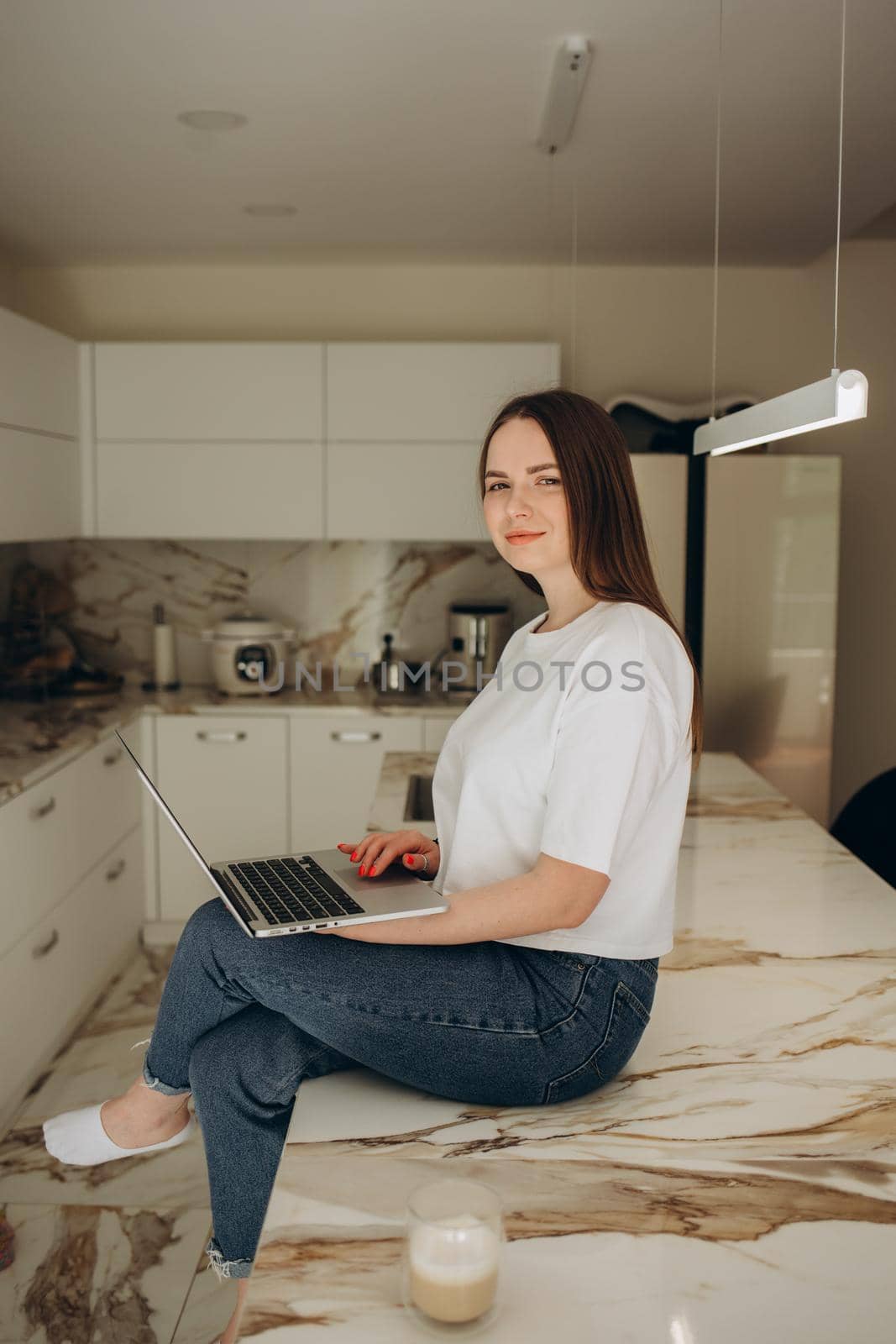 Young woman working from home office. Freelancer using laptop and the Internet for shopping online. Happy girl smiling. Workplace in cozy kitchen. Successful female business. Lifestyle moment