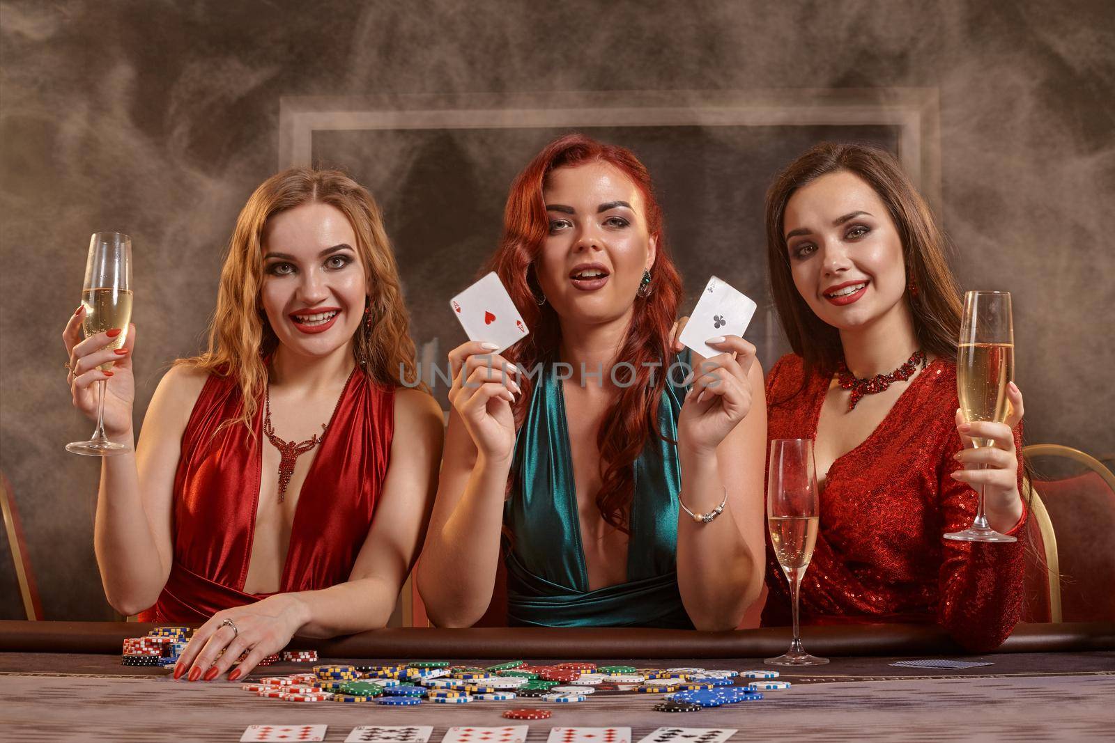 Group of a young wealthy ladies are playing poker at a casino. by nazarovsergey