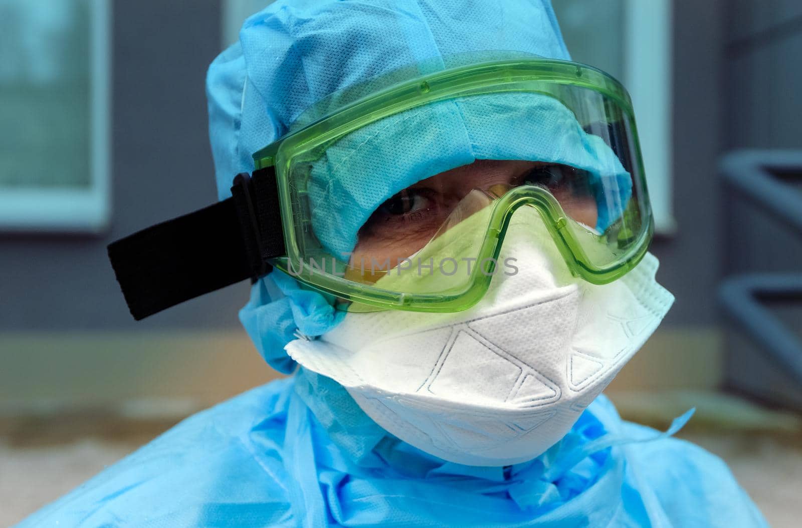 A doctor in a disposable antiepidemic suit in a mask and glasses.