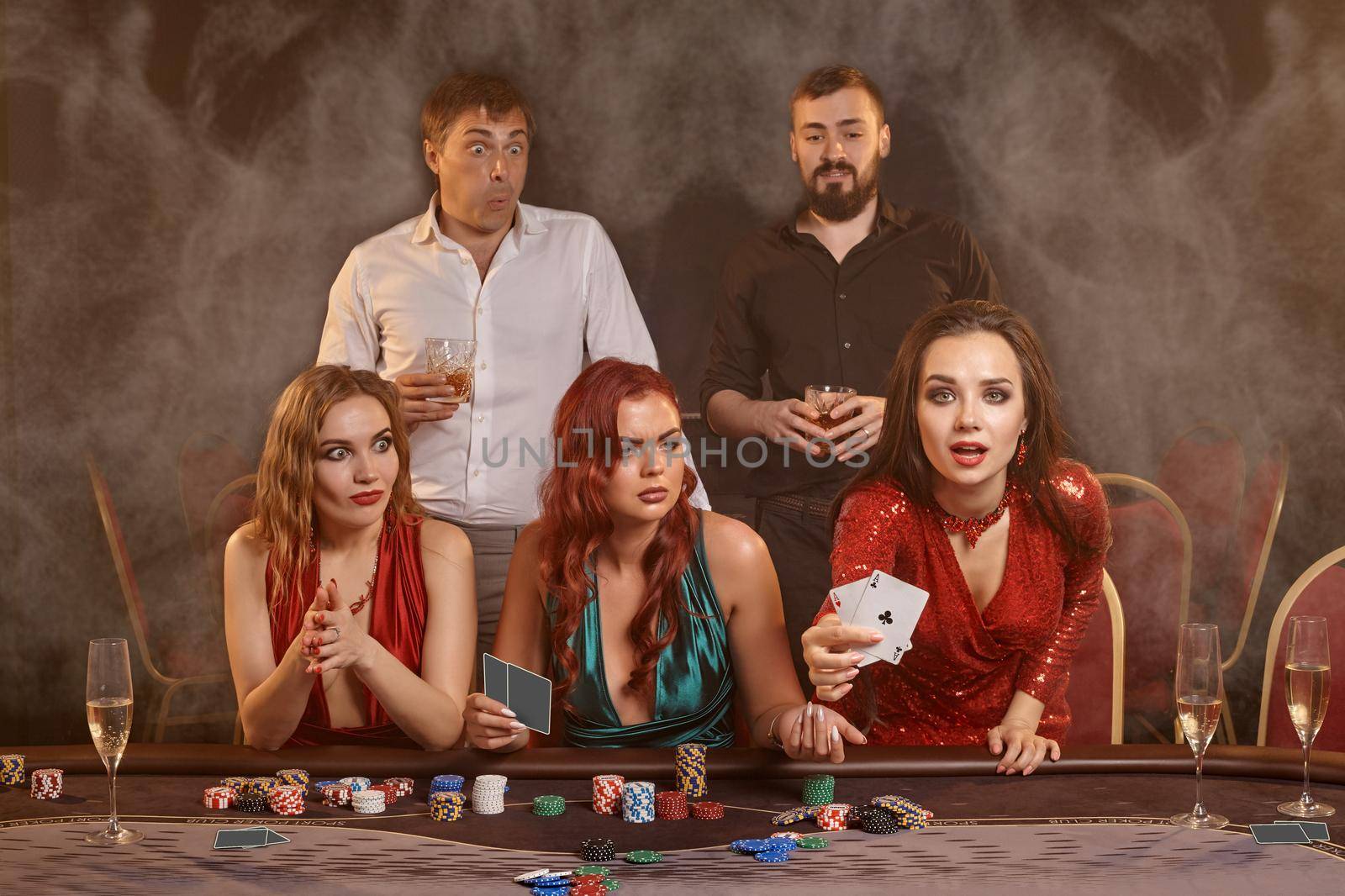 Group of a young wealthy friends are playing poker at a casino. by nazarovsergey