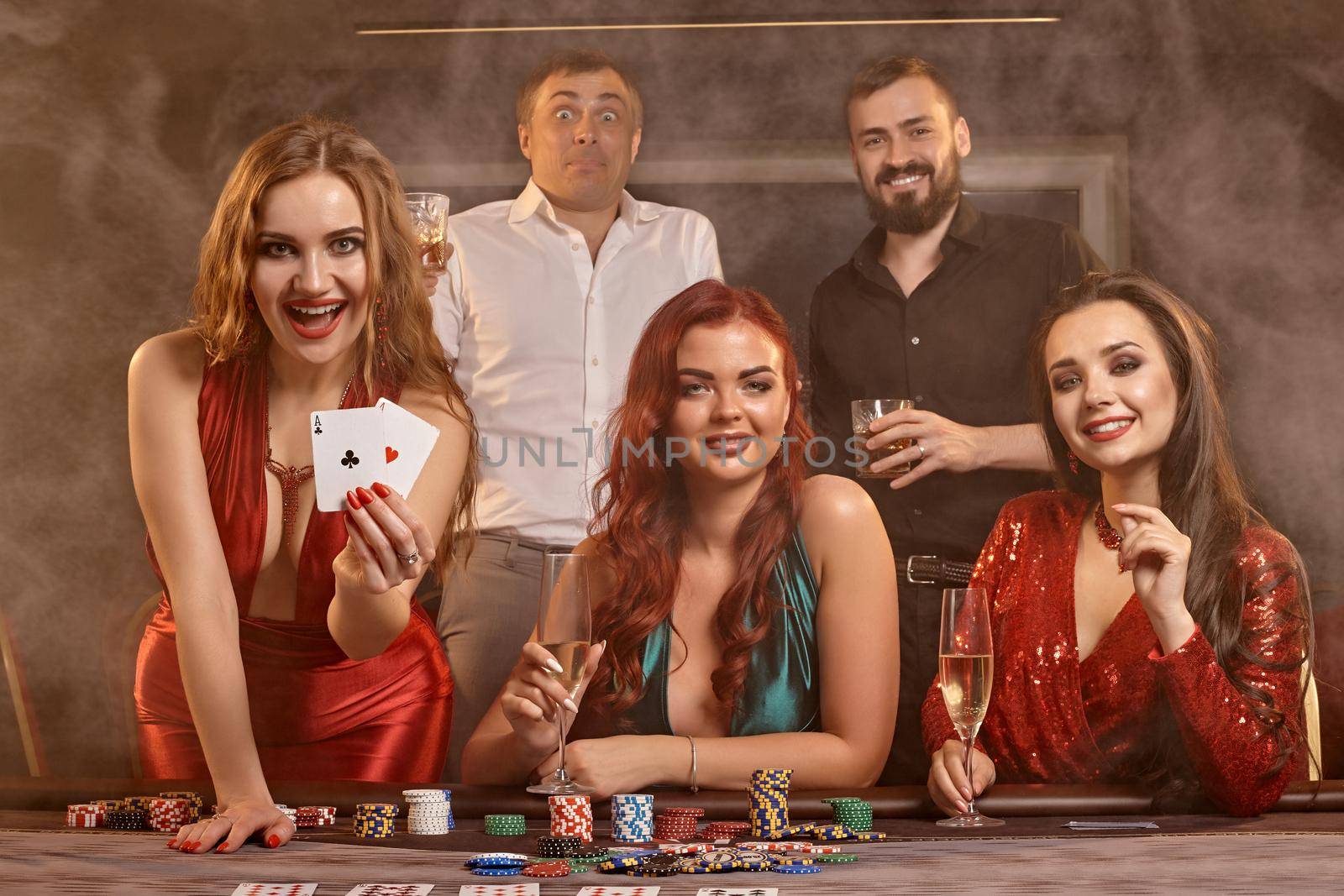 Group of a young wealthy friends are playing poker at a casino. by nazarovsergey