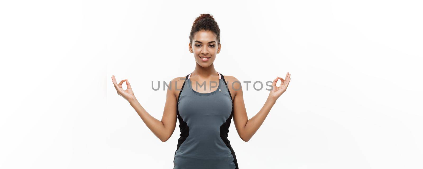 Healthy and Fitness concept - Beautiful American African lady in fitness clothing doing yoga and meditation. Isolated on white background. by Benzoix