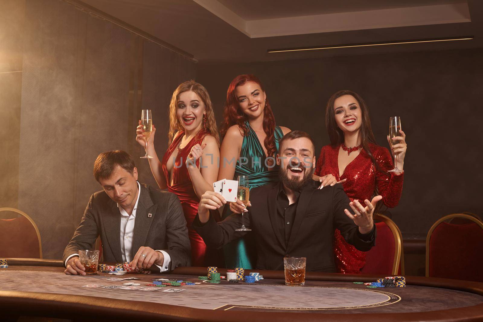 Group of a young wealthy friends are playing poker at a casino. by nazarovsergey