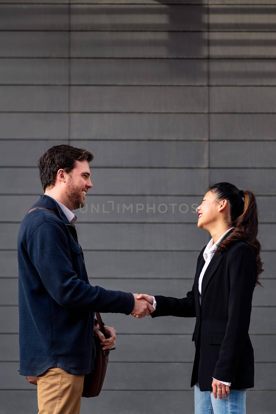 caucasian businessman and asiatic businesswoman shaking hands, concept of entrepreneurship and business, copy space for text