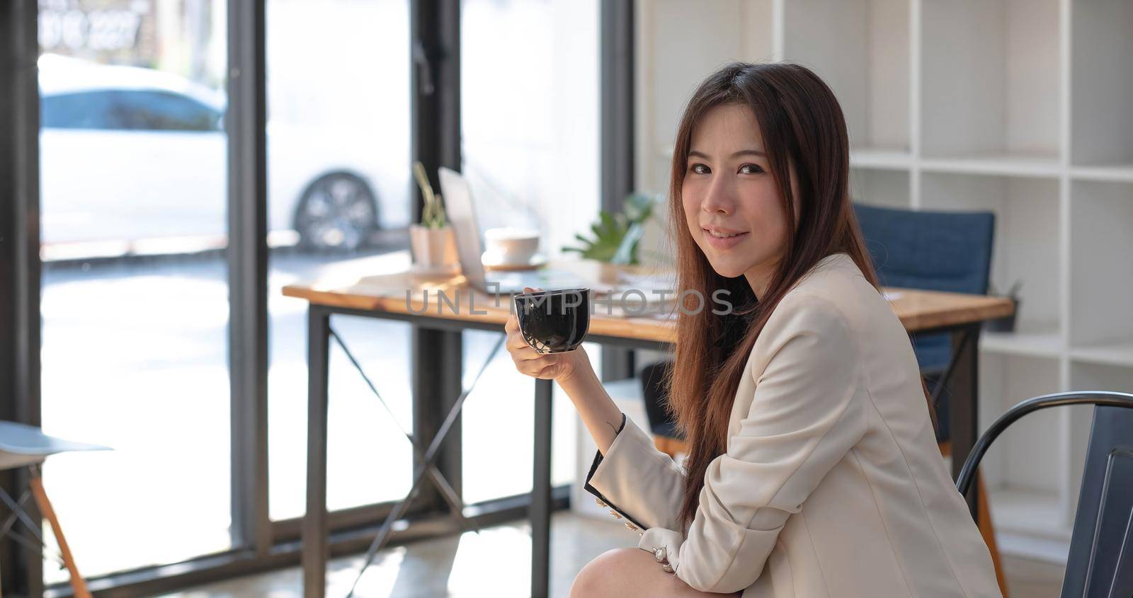 Charming Asian woman working at the office using a laptop Looking at the camera..