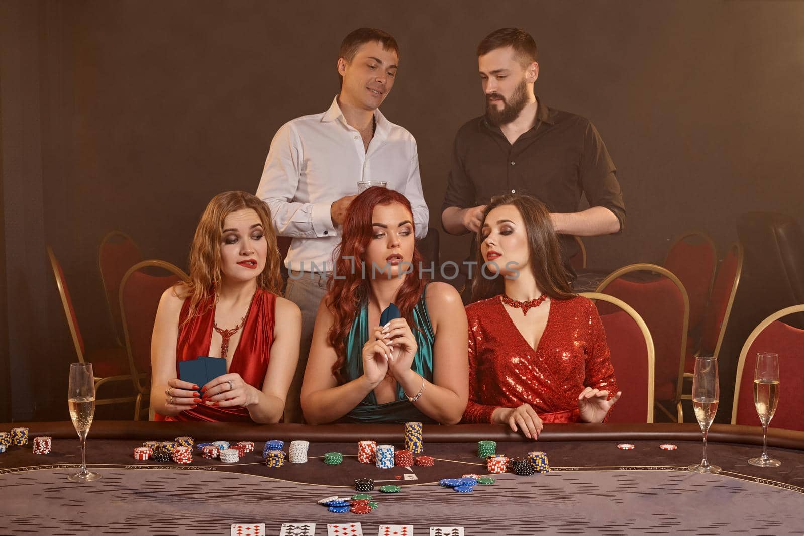 Group of a young wealthy friends are playing poker at a casino. by nazarovsergey