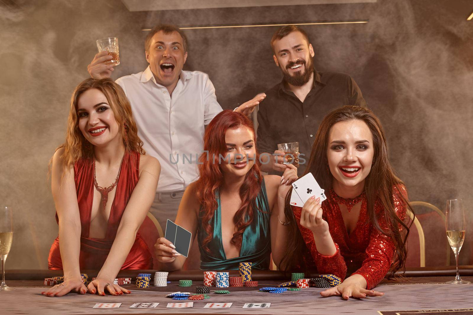 Group of a young wealthy friends are playing poker at a casino. by nazarovsergey