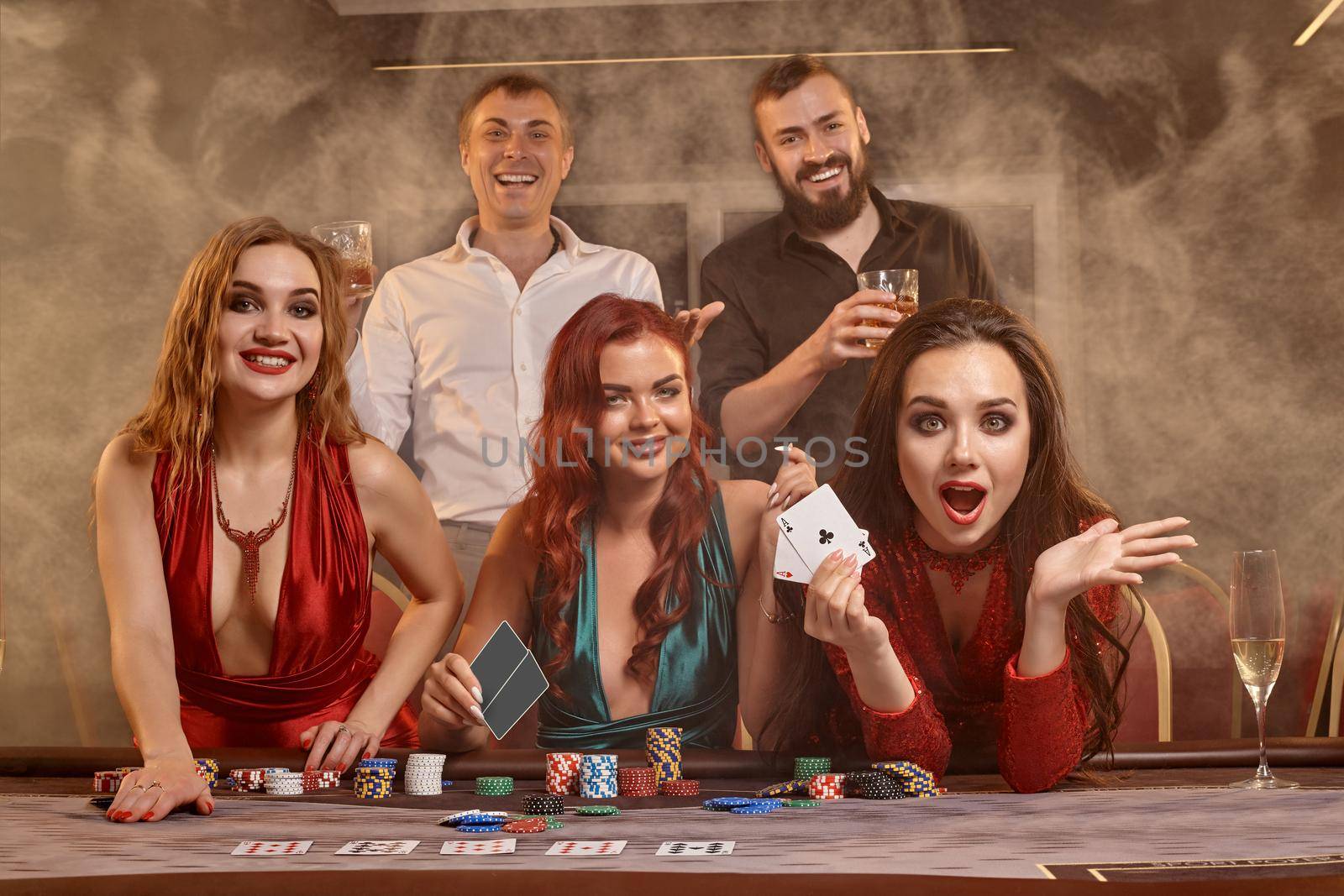 Group of a young wealthy friends are playing poker at a casino. by nazarovsergey