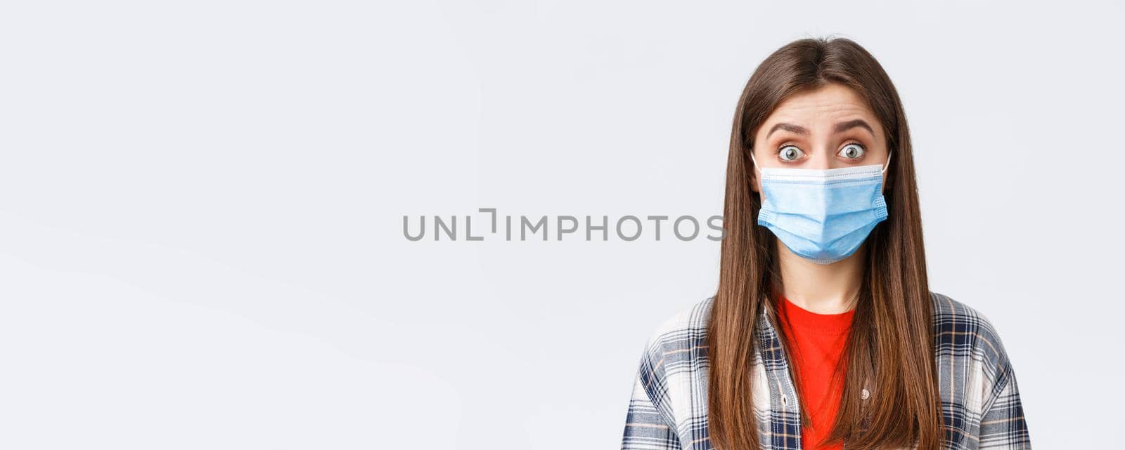 Coronavirus outbreak, leisure on quarantine, social distancing and emotions concept. Close-up of intrigued, surprised woman hear interesting news, wear medical mask, widen eyes by Benzoix